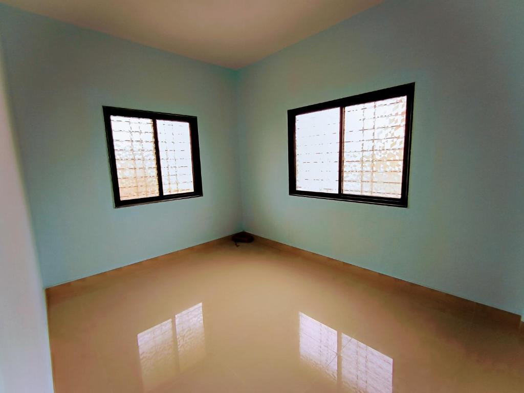 an empty room with two windows in it at Rathore Nivas in Pune