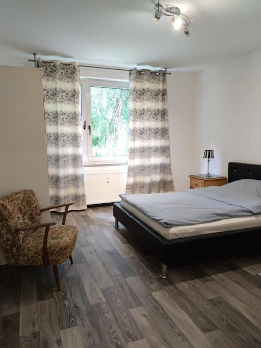 a bedroom with a bed and a chair and a window at Wohnung am Waldrand in Melle