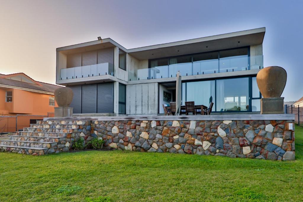 a large house with a stone wall at Mi Amor Myoli Beach in Sedgefield