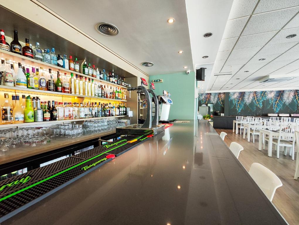 a bar with a long counter with bottles of alcohol at Bayside Salgados in Albufeira