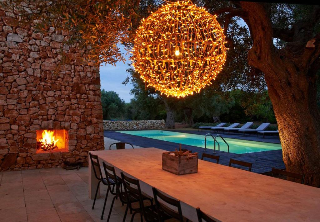 a large chandelier hangs over a table and a pool at Bosco degli Ulivi in Morciano di Leuca