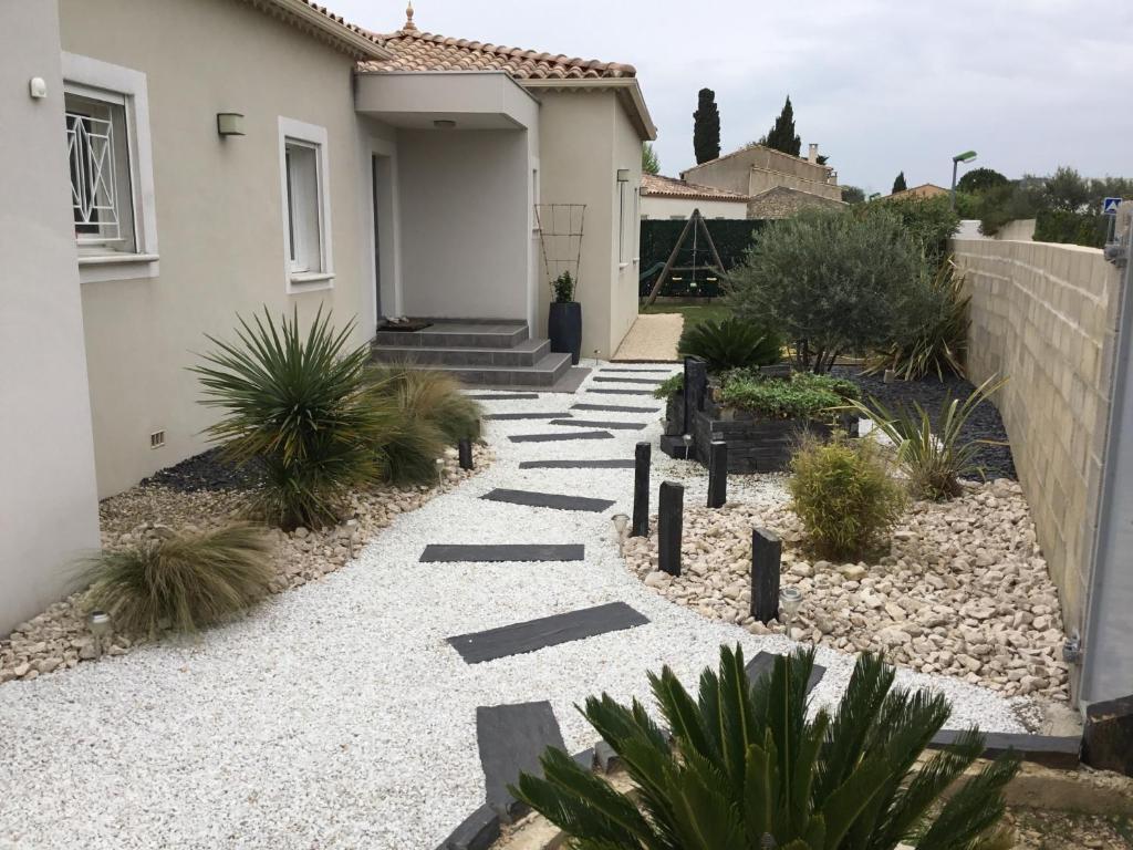 une passerelle menant à une maison avec des plantes dans l'établissement Villa moderne piscine privée calme soleil près de Nîmes, à Clarensac
