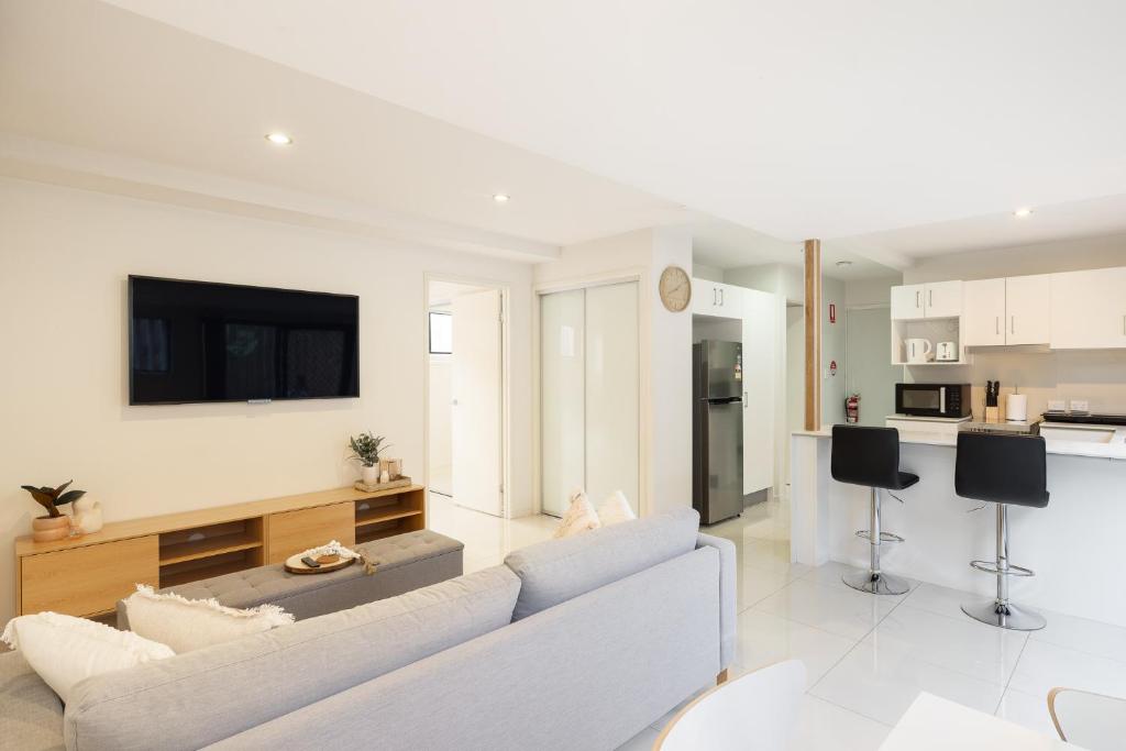 a white living room with a couch and a kitchen at Super Host! 2 bedrooms, Restaurants & Train in Brisbane