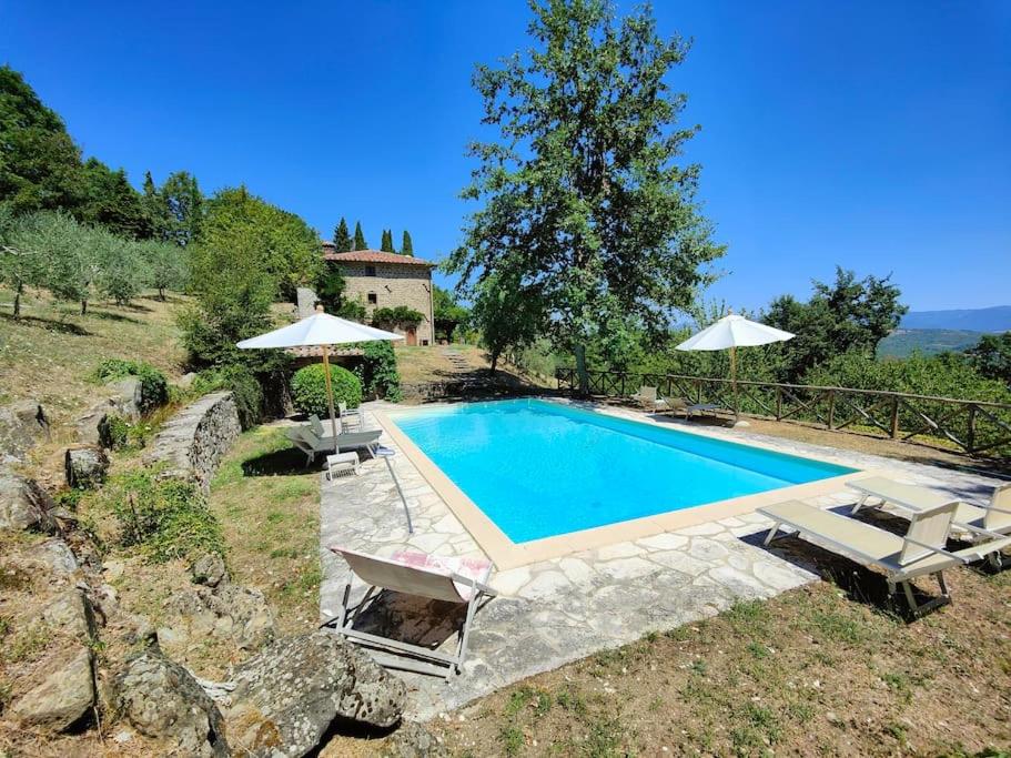 - une piscine dans une cour avec des chaises et des parasols dans l'établissement CASA CAROLE - Lake View Villa, à Caprese Michelangelo