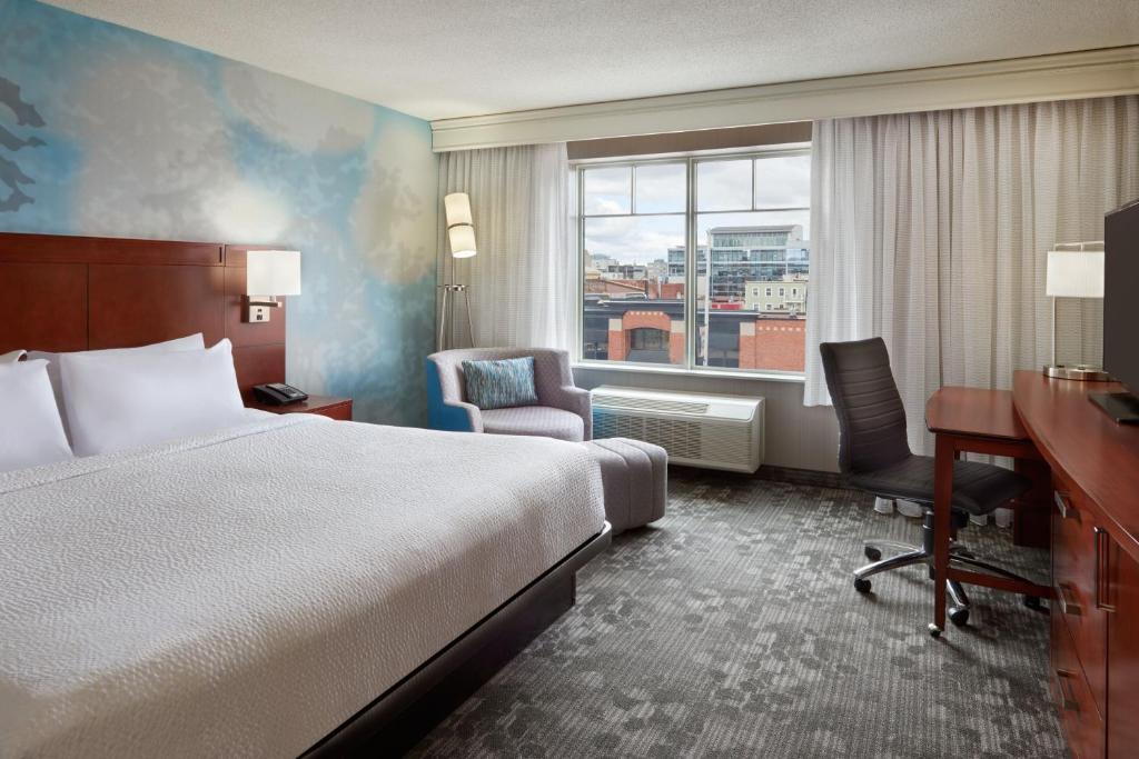 a hotel room with a bed and a desk and a window at Courtyard by Marriott Ottawa Downtown in Ottawa