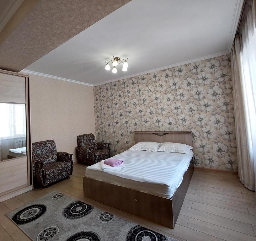 1 dormitorio con 1 cama y 2 sillas en Elite Apartment in street Orozbekova 2 en Bishkek