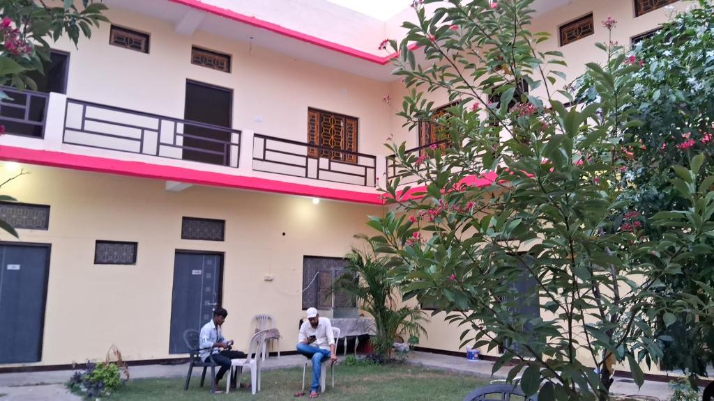 two people sitting in chairs in front of a building at Blue Sky Homestay in Khajurāho