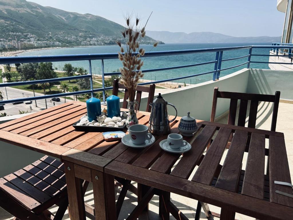 una mesa de madera en un balcón con vistas al océano en Casa con vista mare en Vlorë