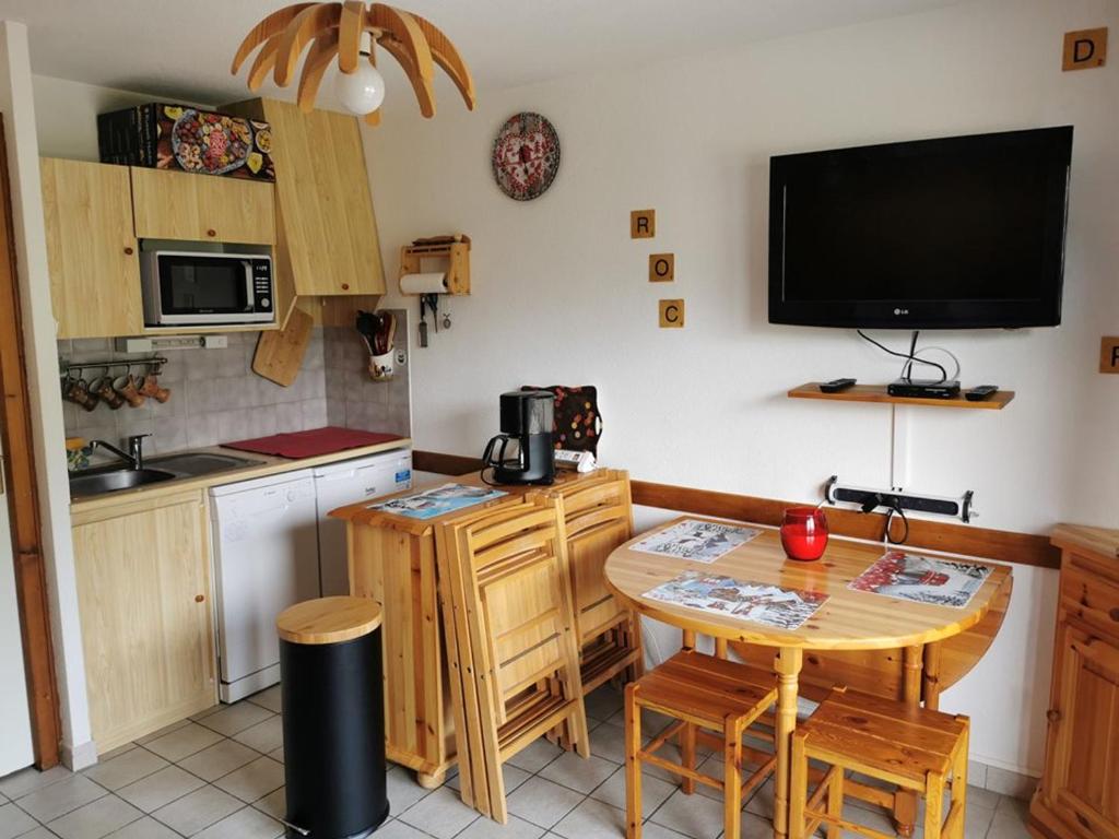 Il comprend une cuisine avec une petite table et une télévision murale. dans l'établissement Location 2 pièces proche télécabine, 4 pers, parking - FR-1-573-67, à Saint-Jean-dʼAulps