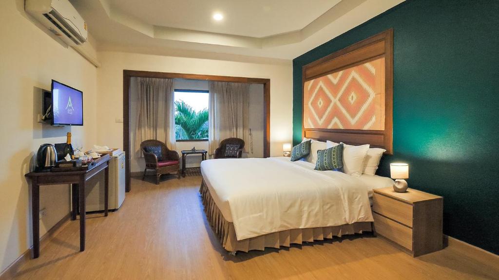 チェンライにあるSiam Avari Hotel, Chiang Raiの大型ベッドとテレビが備わるホテルルームです。