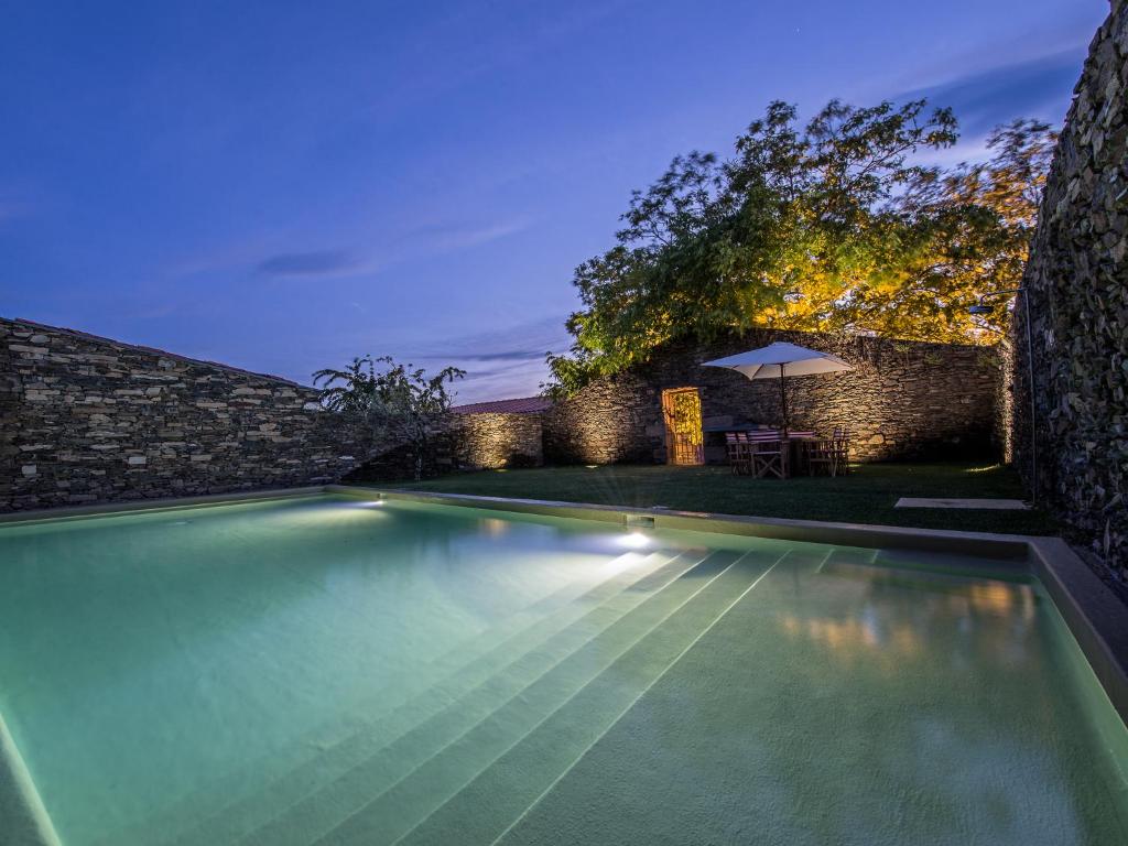 a swimming pool at night with a table and an umbrella at Morgadio da Calcada in Provesende