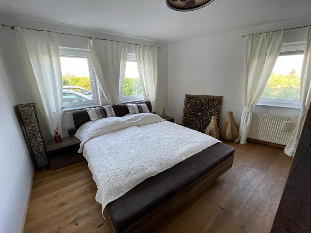 a bedroom with a large bed and two windows at Ferienwohnung in Maikammer in Maikammer