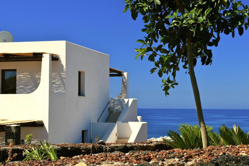 a white house with the ocean in the background at Kuddie Rosse Eco-Friendly Residence in Pantelleria
