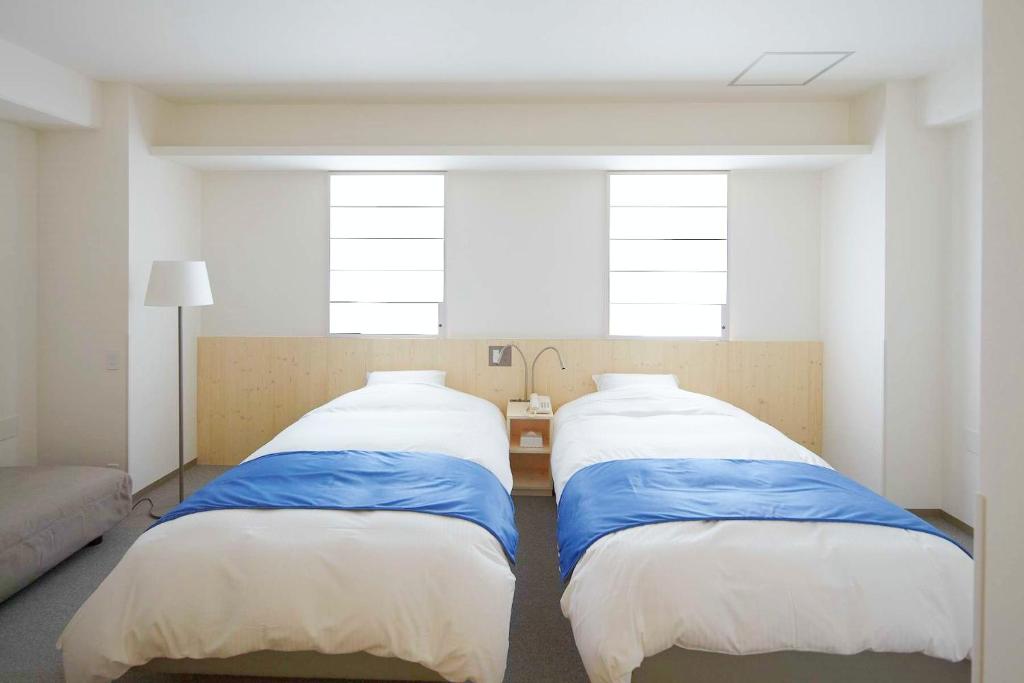 2 camas en una habitación con 2 ventanas en Shin-Osaka Station Hotel, en Osaka