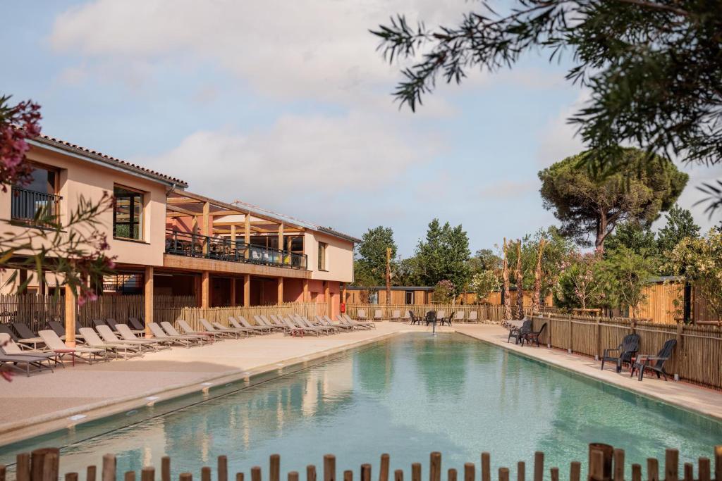 a swimming pool with chairs and a building at Beach Resort Agde in Le Grau-dʼAgde