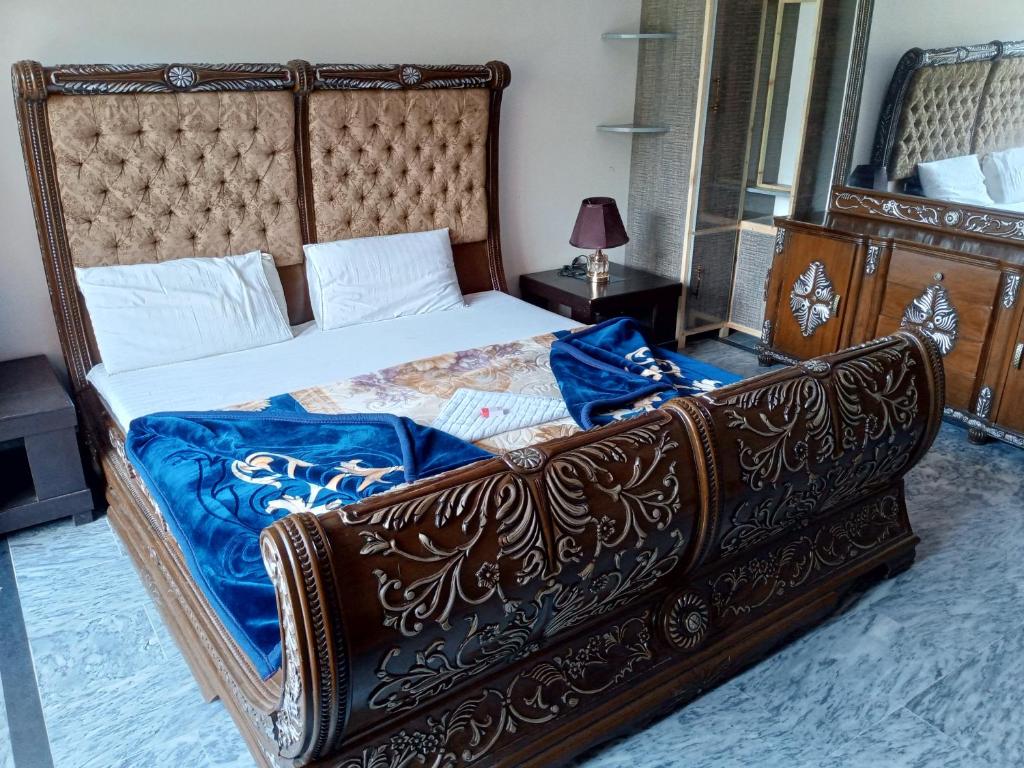 a bedroom with a large bed with a wooden frame at Hotel Red Roof & Restaurant in Abbottabad