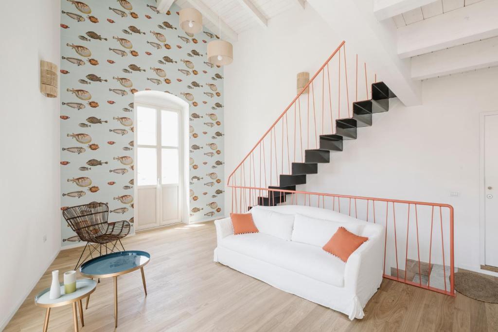 uma sala de estar com um sofá branco e uma escada em AltaMarea - Ampi spazi in Centro storico em Carloforte