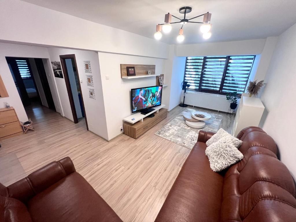 sala de estar con sofá de cuero y TV de pantalla plana en CRISTAL Home Boutique Apartment 1 - Confort, Spatios, Linistit, Zona de interes, en Craiova