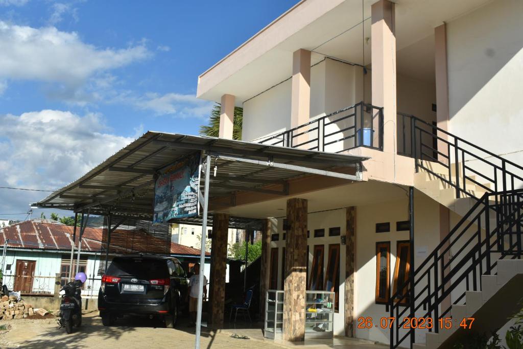 een gebouw waar een auto voor geparkeerd staat bij JOHN'S HOMESTAY in Labuan Bajo