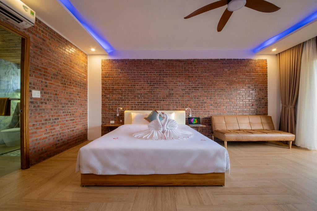 a bedroom with a bed and a brick wall at Hoi An Golden Bamboo An Bang Beach Villa & Spa in Hoi An