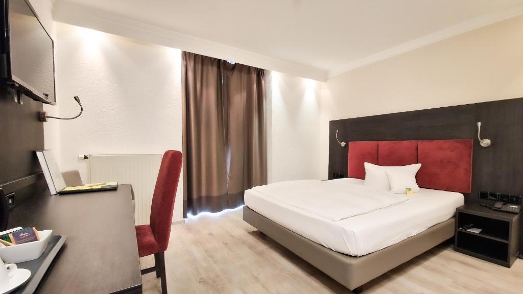1 dormitorio con cama blanca y cabecero rojo en Astralis Hotel Domizil, en Walldorf