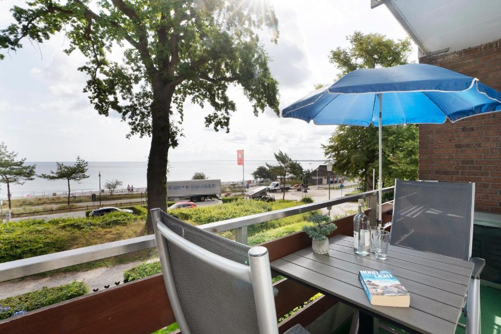 una mesa con una sombrilla azul en el balcón en Am Hang 15 Seeblick App 7 en Scharbeutz