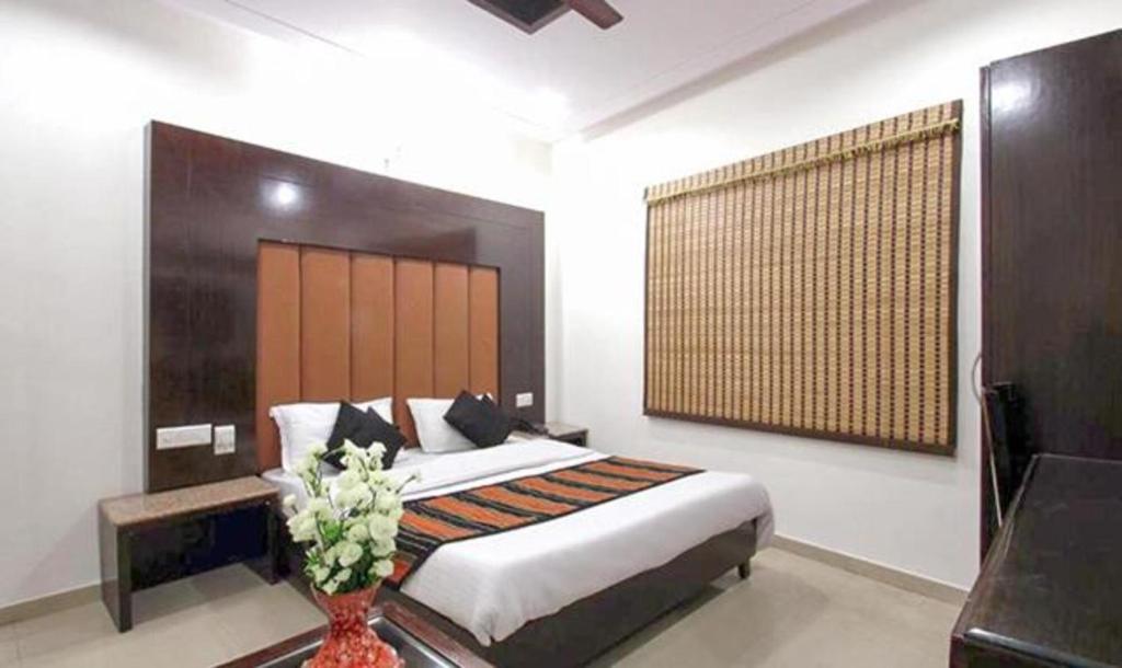 a bedroom with a bed and a vase with flowers at FabHotel Station 3 in New Delhi
