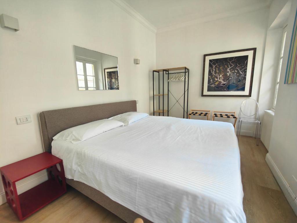ミラノにあるSant'Andrea Charme Apartmentsのベッドルーム(白い大型ベッド1台、赤いスツール付)