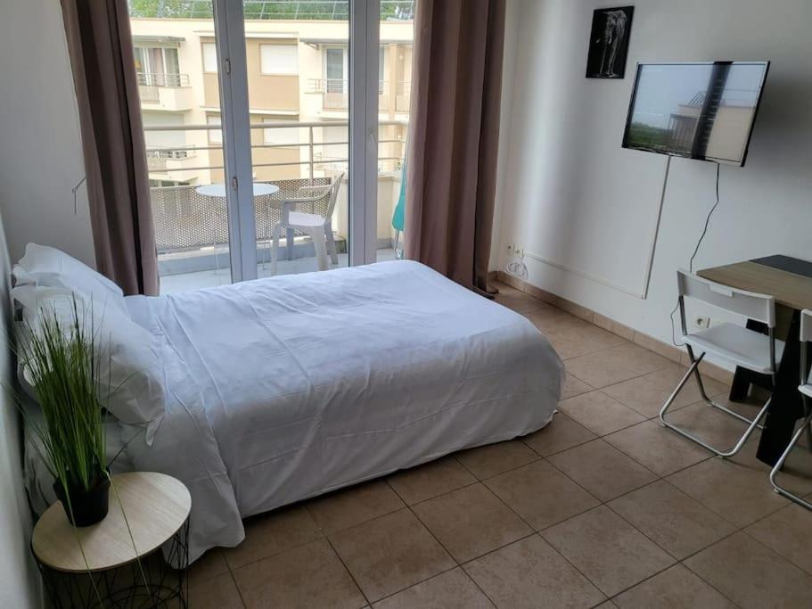a bedroom with a bed and a desk and a window at Disney Paris Appartement in Montévrain