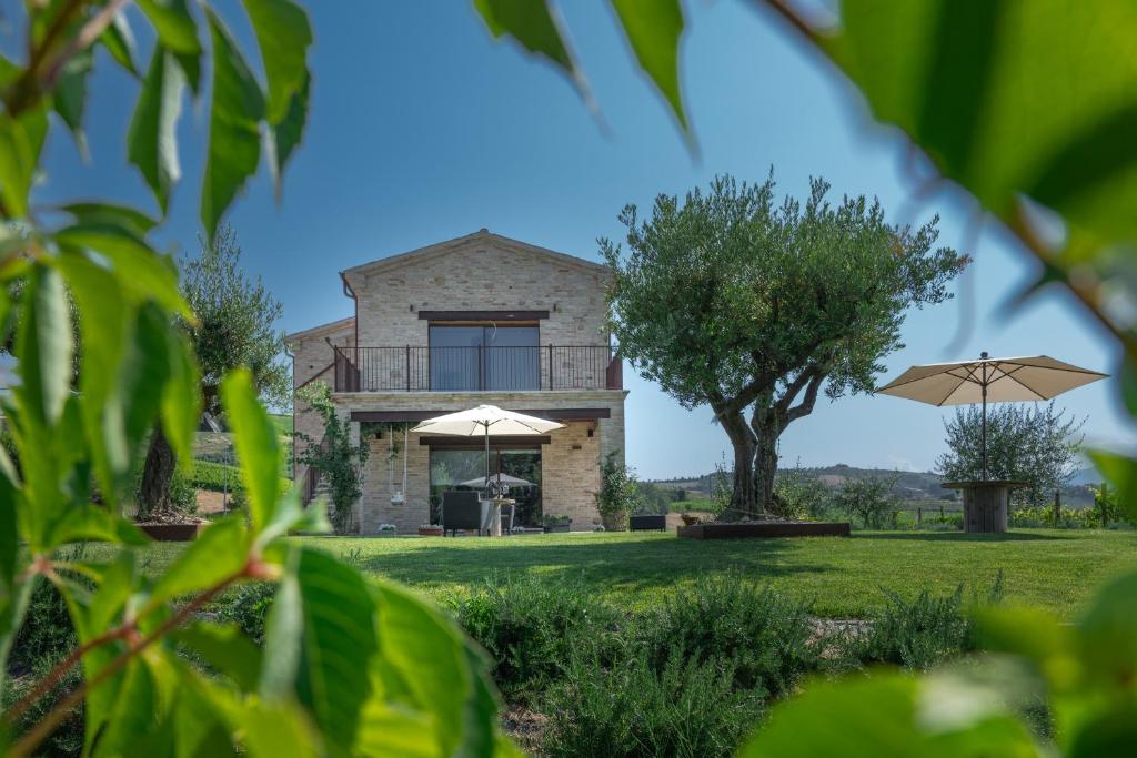 une maison au milieu d'un champ avec des parapluies dans l'établissement Agriturismo San Nicolino, à Offida