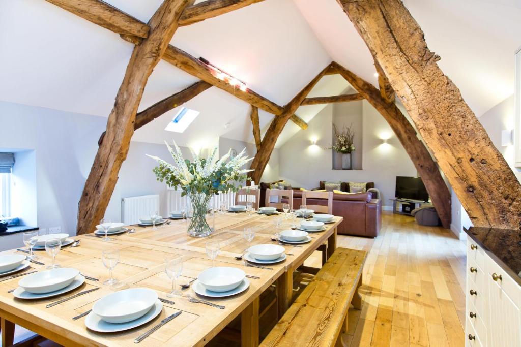 a large wooden table in a living room with exposed beams at Cruck'd Barn in Buxton