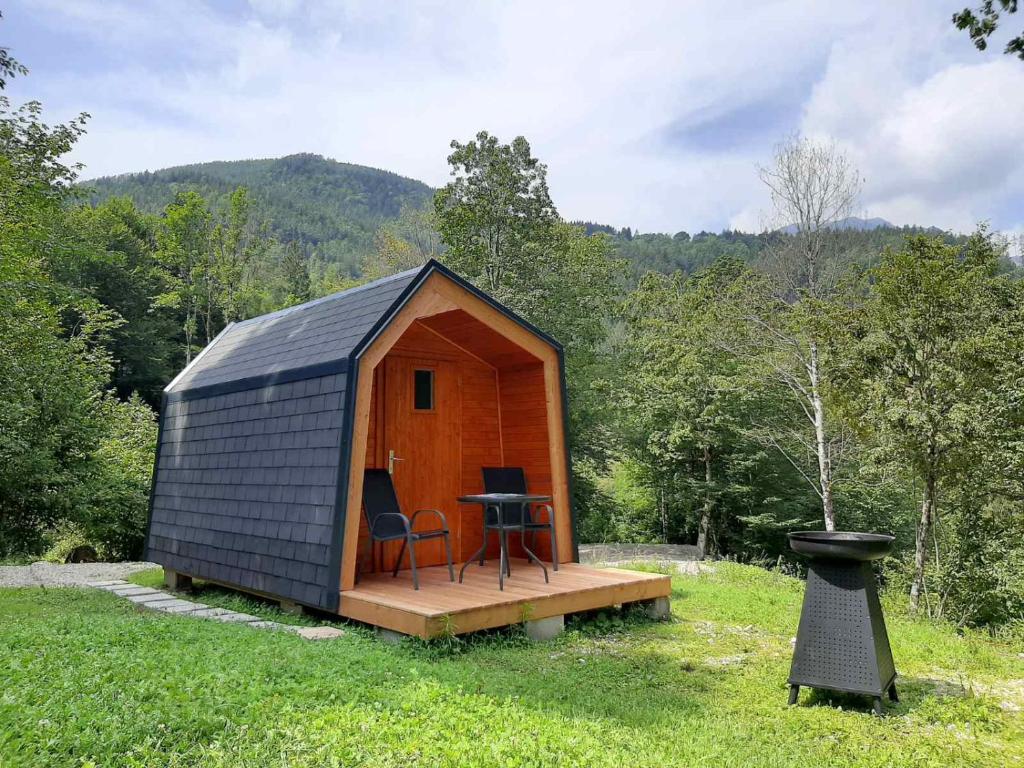a small cabin with a table and chairs in a field at Camping & Glamping Grintovec in Preddvor