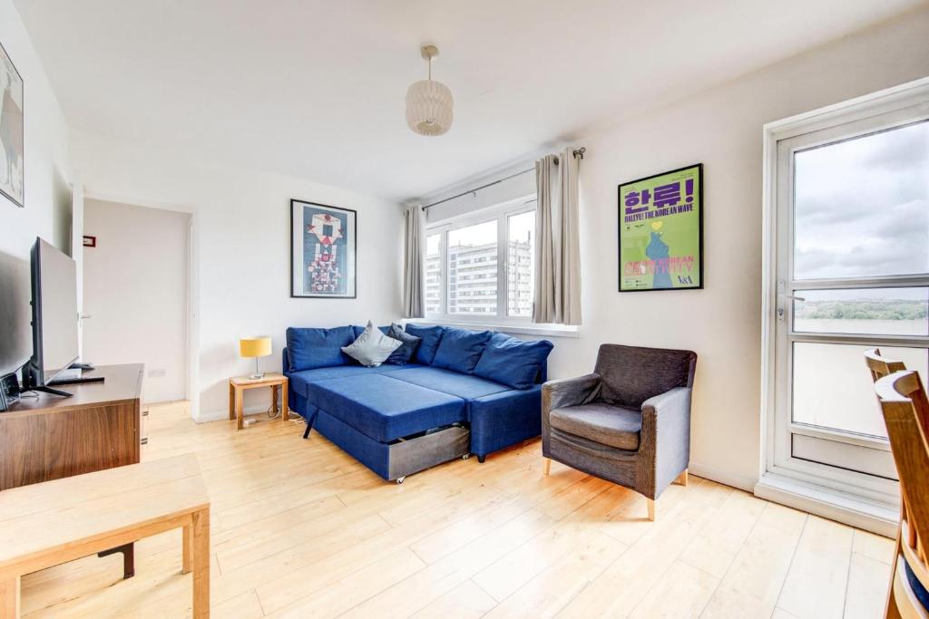 a living room with a blue couch and a chair at GuestReady - Penthouse Flat in Trendy Peckham in London