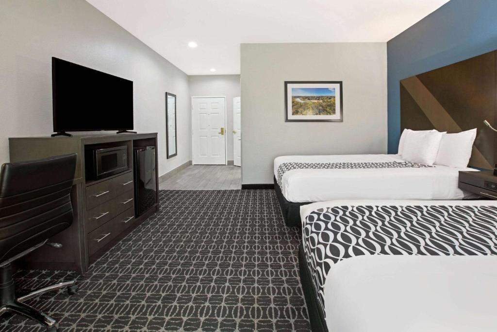 a hotel room with two beds and a flat screen tv at La Quinta by Wyndham Sulphur Springs in Sulphur Springs