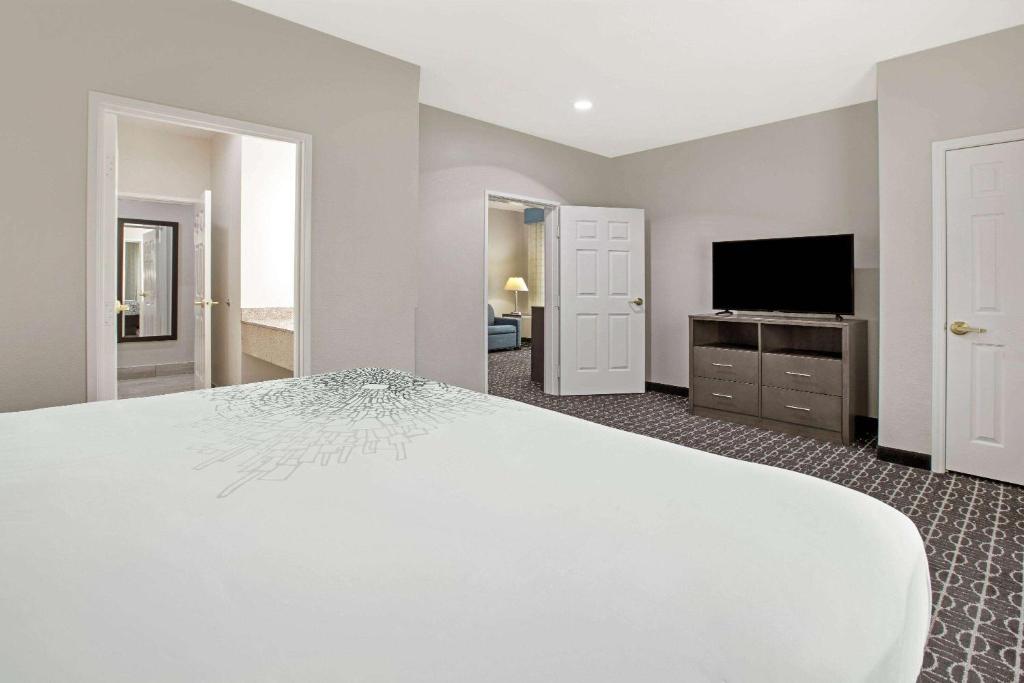 a large bedroom with a white bed and a flat screen tv at La Quinta by Wyndham Sulphur Springs in Sulphur Springs