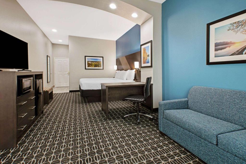 a hotel room with a bed and a couch at La Quinta by Wyndham Sulphur Springs in Sulphur Springs