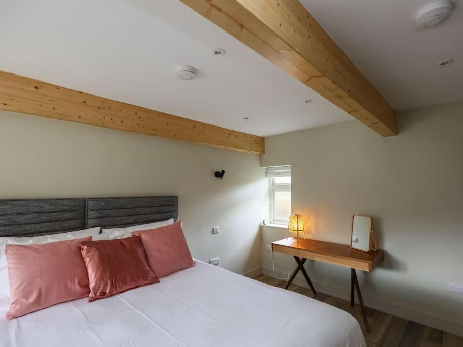 a bedroom with a white bed and a wooden table at Spacious 1-bed apartment with super king or twin in central Charlbury, Cotswolds in Charlbury