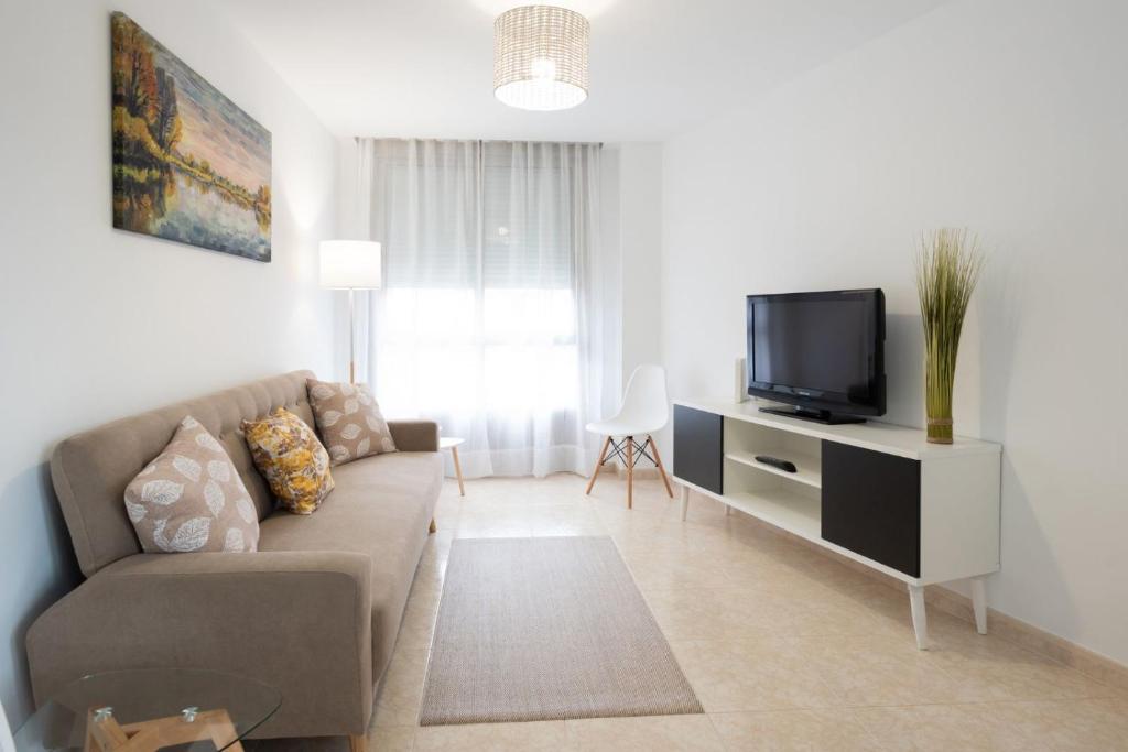 a living room with a couch and a tv at UNA HABITACIÓN PLAYA GRANDE MIÑO in Miño