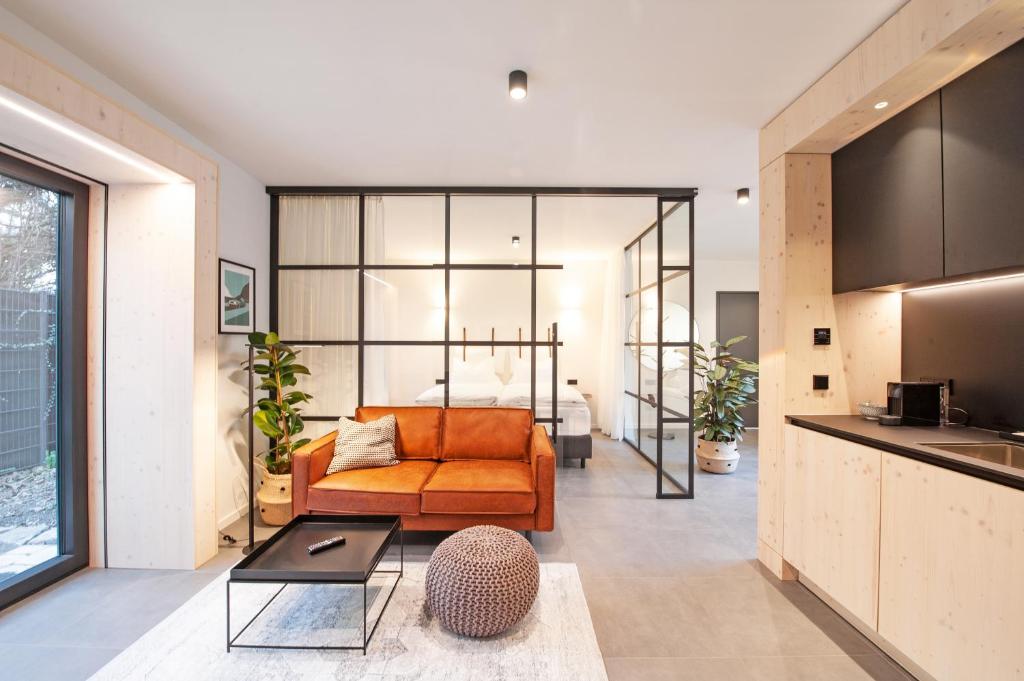 an open living room with an orange couch and a kitchen at Mono Design Apartments in Stuttgart