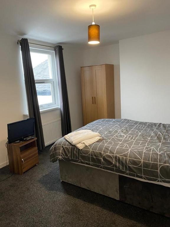 a bedroom with a bed and a tv and a window at 2 Bedroom Flat with free parking in Manchester in Manchester