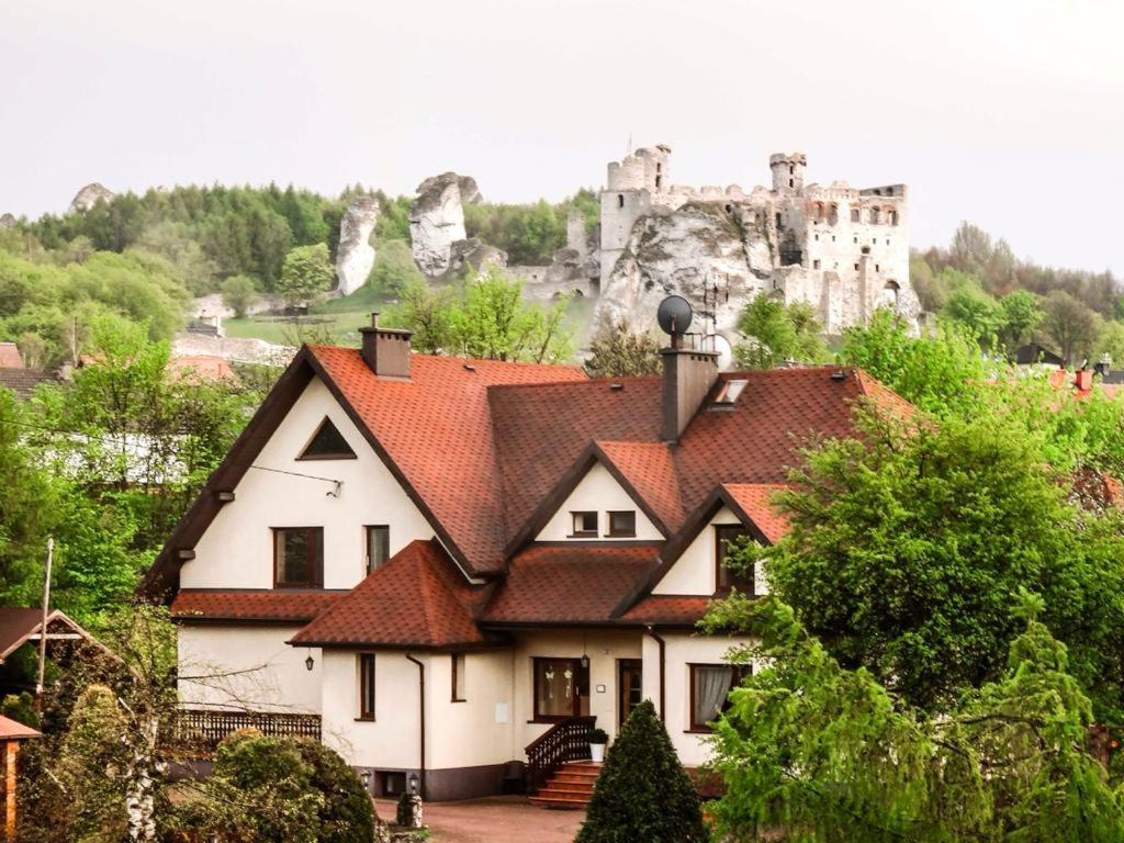 una casa con un castillo en el fondo en SKALNY apartamenty, pokoje, en Ogrodzieniec