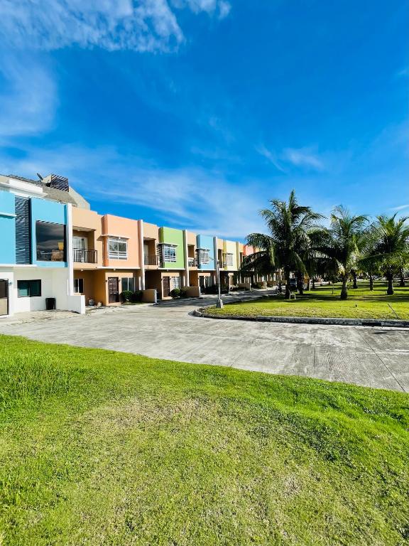 a large building with palm trees in front of it at Nila's Staycation House in Dauis