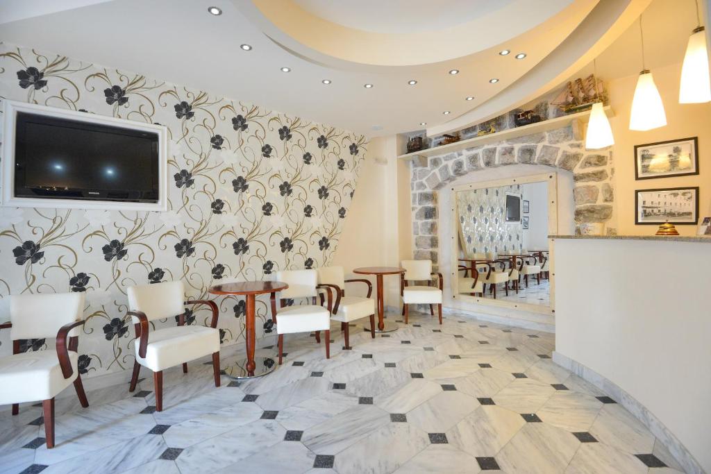 a restaurant with tables and chairs and a tv on the wall at Hotel Villa Perla Di Mare in Budva