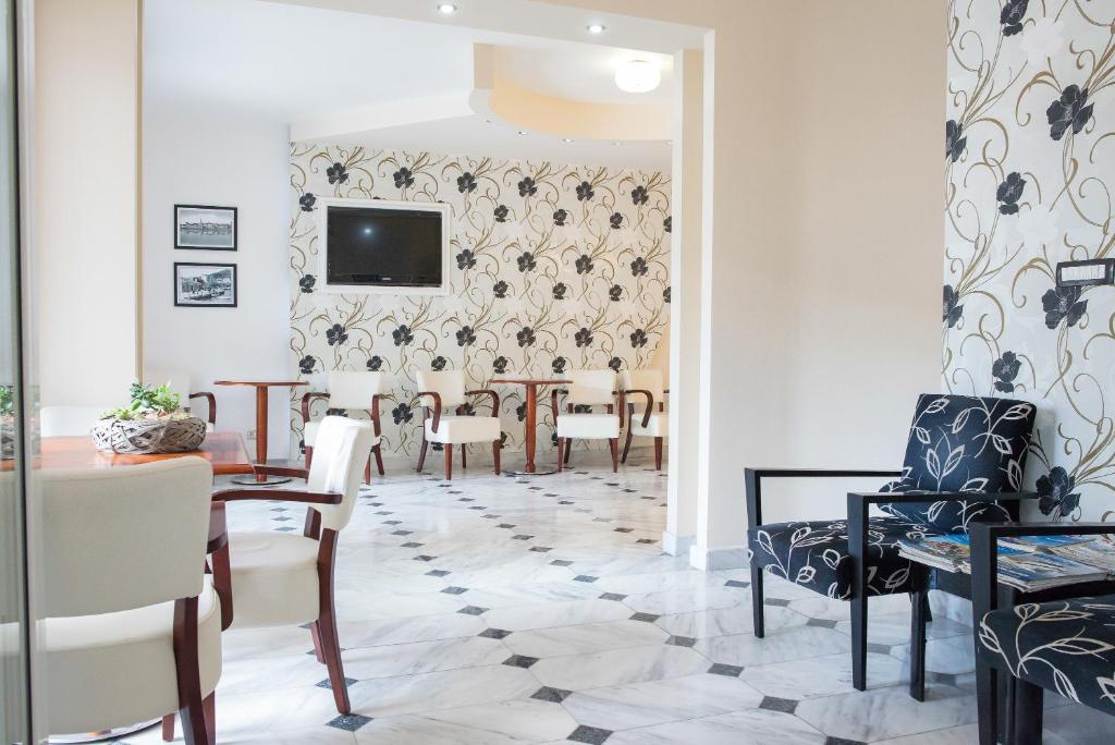 a dining room with tables and chairs and a wall covered in floral wallpaper at Hotel Villa Perla Di Mare in Budva