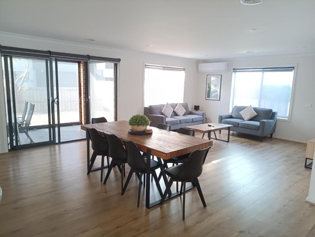 a living room with a table and chairs and a couch at Captains Edge- Brand New 3 bedroom spacious home, private afresco & yard central to Paynesville CBD in Paynesville