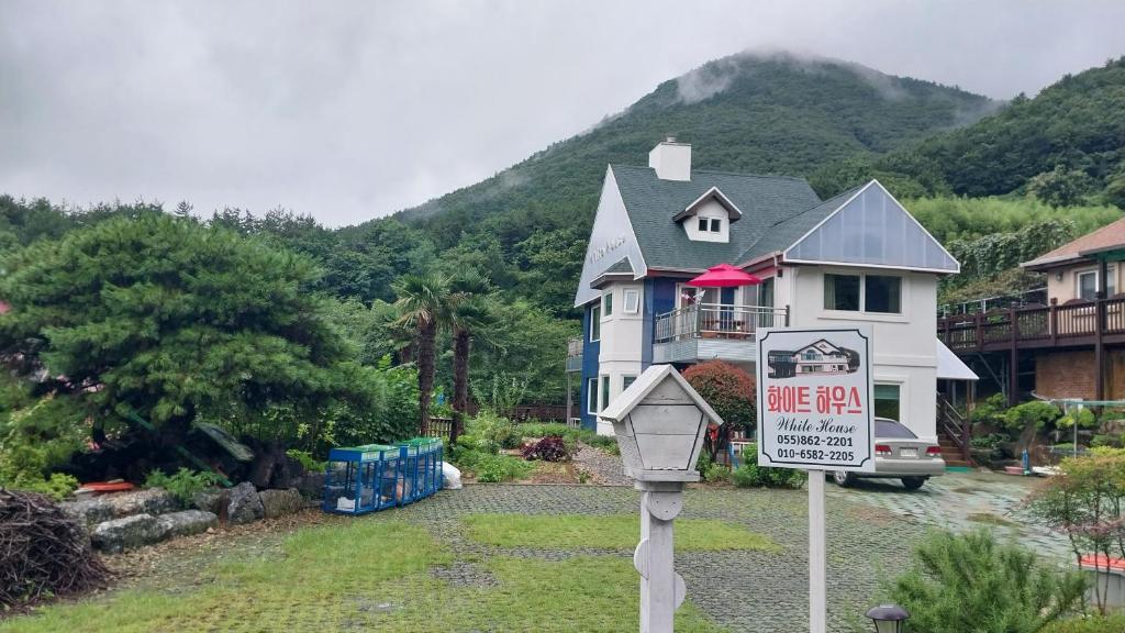 une maison avec un panneau de vente devant elle dans l'établissement White House, à Namhae