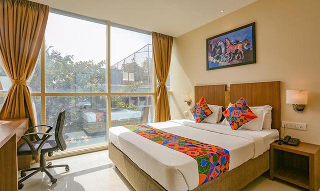 a bedroom with a bed and a large window at FabHotel Royal Mumbai International Airport in Mumbai