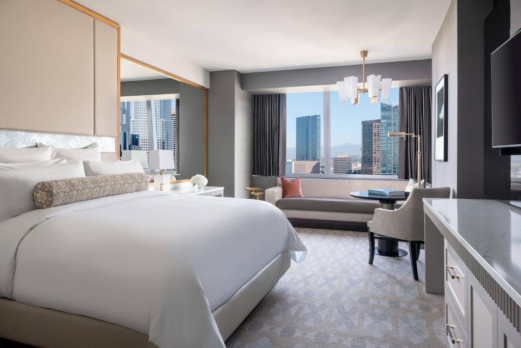 a bedroom with a large white bed and a living room at The Ritz-Carlton, Los Angeles L.A. Live in Los Angeles