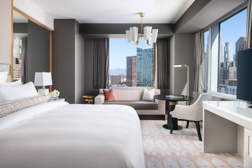 a bedroom with a large white bed and a living room at The Ritz-Carlton, Los Angeles L.A. Live in Los Angeles