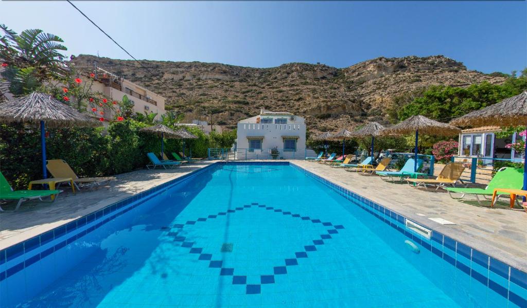 una piscina con sillas y sombrillas en Hotel Coral Matala en Matala